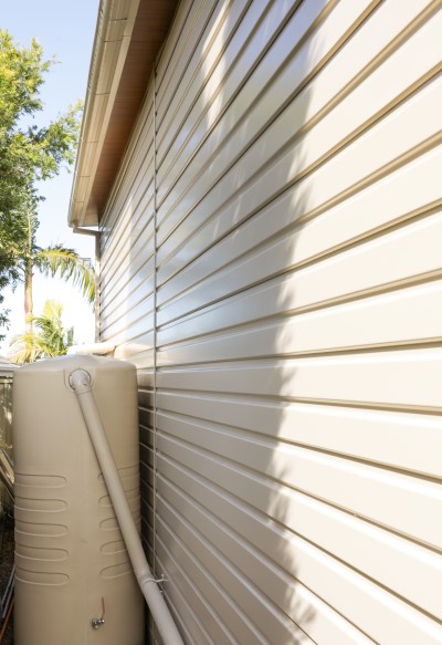 Side wall of an off white steel shed with a water tank 