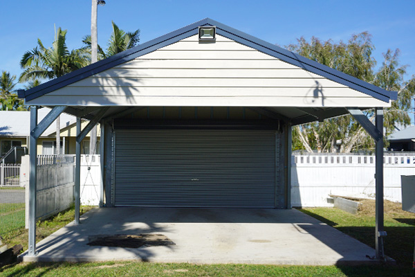 Gable carport in cream with blue trim with double roller door
