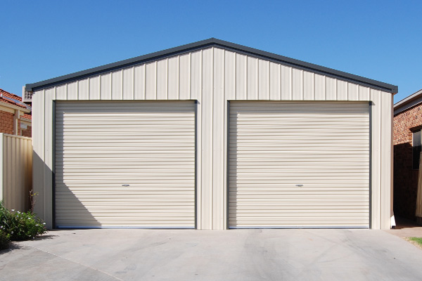 Double garage with gable roof in white against a blue sky